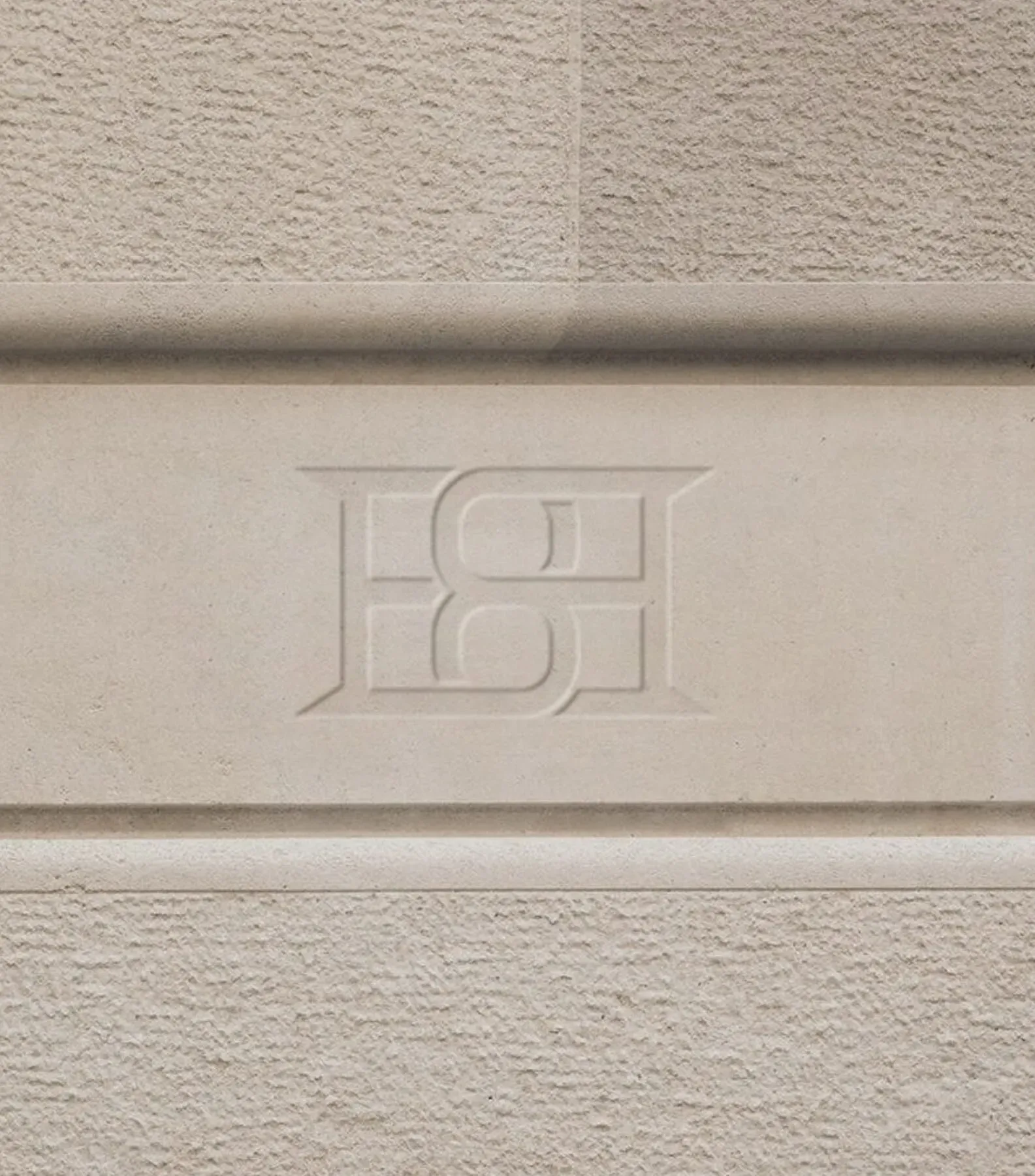 Decorative architectural stone band with embossed monogram detail on building facade