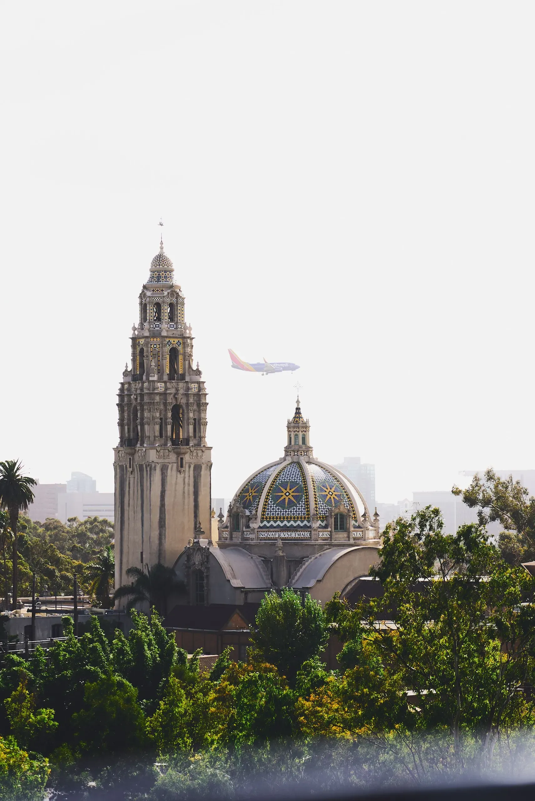Historic church with bell tower and golden dome in San Diego surrounded by green trees