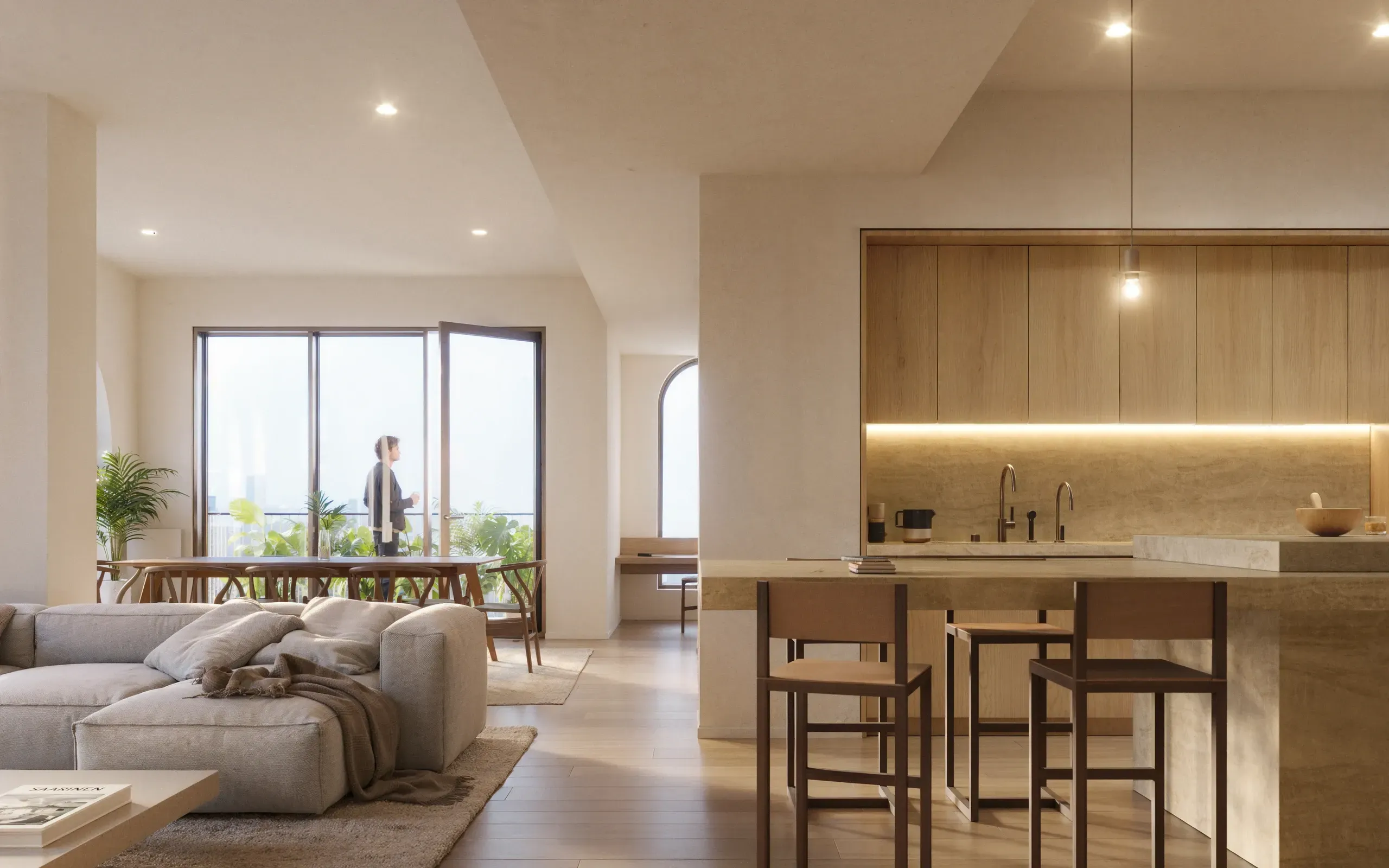 Modern open-concept apartment with beige sectional sofa, kitchen island with bar seating, and large windows overlooking city views.